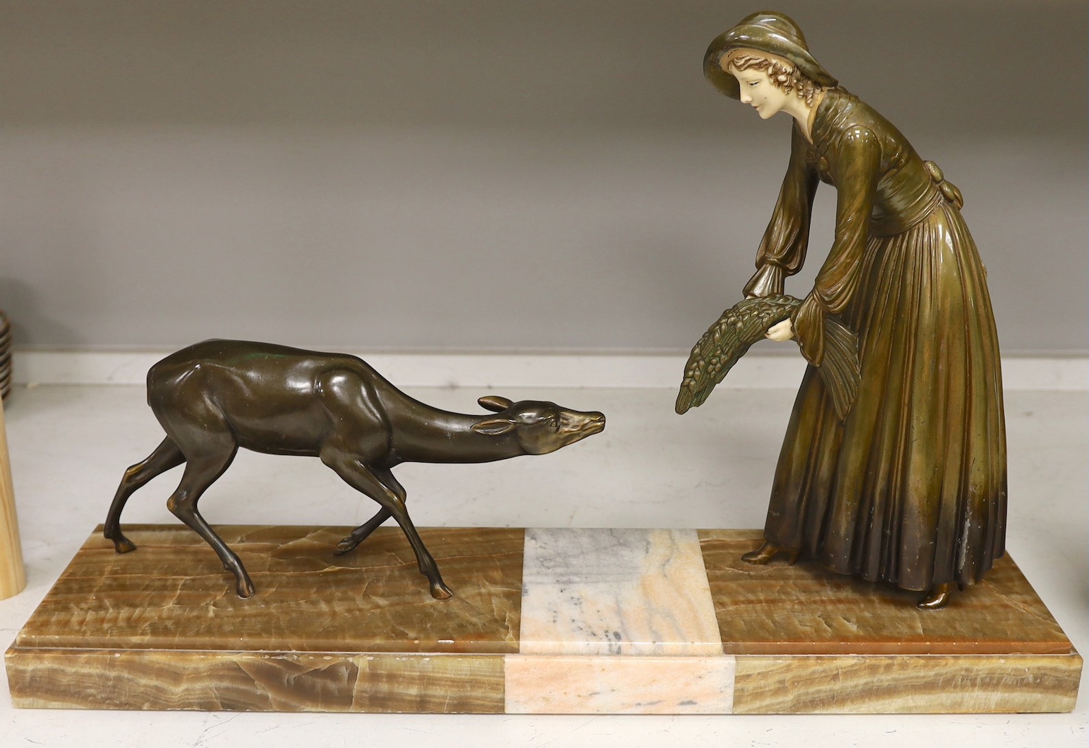 An Art Deco painted spelter model of a peasant girl feeding a deer with faux ivory mounts, the marble base signed ‘Scali’. Length 68cm